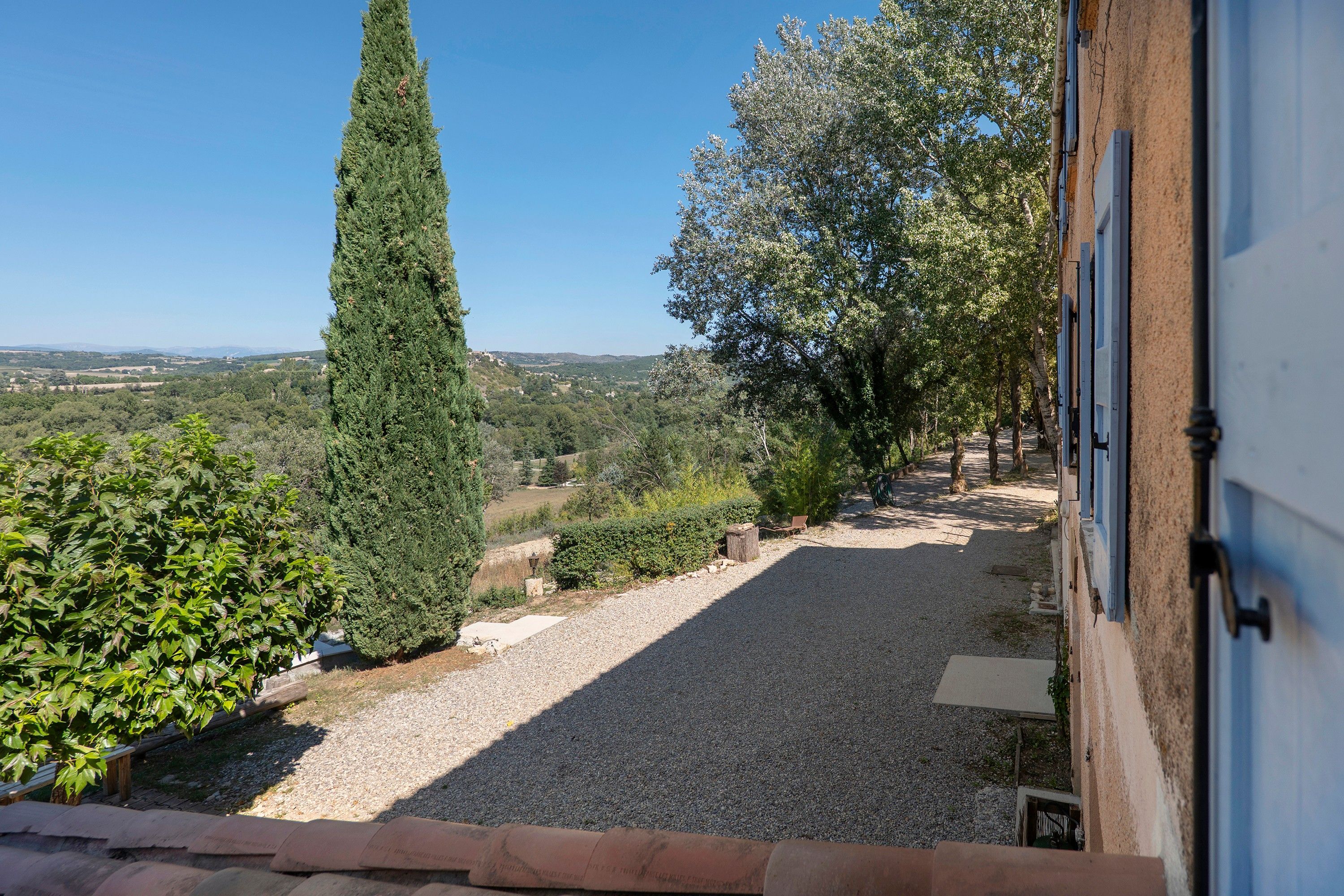 A gravel pathway leading to a building with a view of a rural landscape.