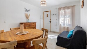 Un coin repas avec une table en bois, des chaises, un ventilateur de plafond et une fenêtre avec des rideaux.