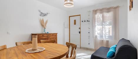 Un coin repas avec une table en bois, des chaises, un ventilateur de plafond et une fenêtre avec des rideaux.