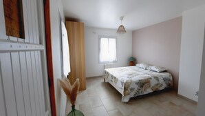 Un dormitorio con cama, ventana, radiador y lámpara colgante.