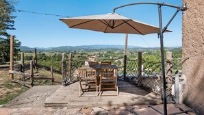 A wooden deck with a table and chairs, a rope barrier, and a view of distant hills. - Mas la bella vista - Caliente (Dauphin)