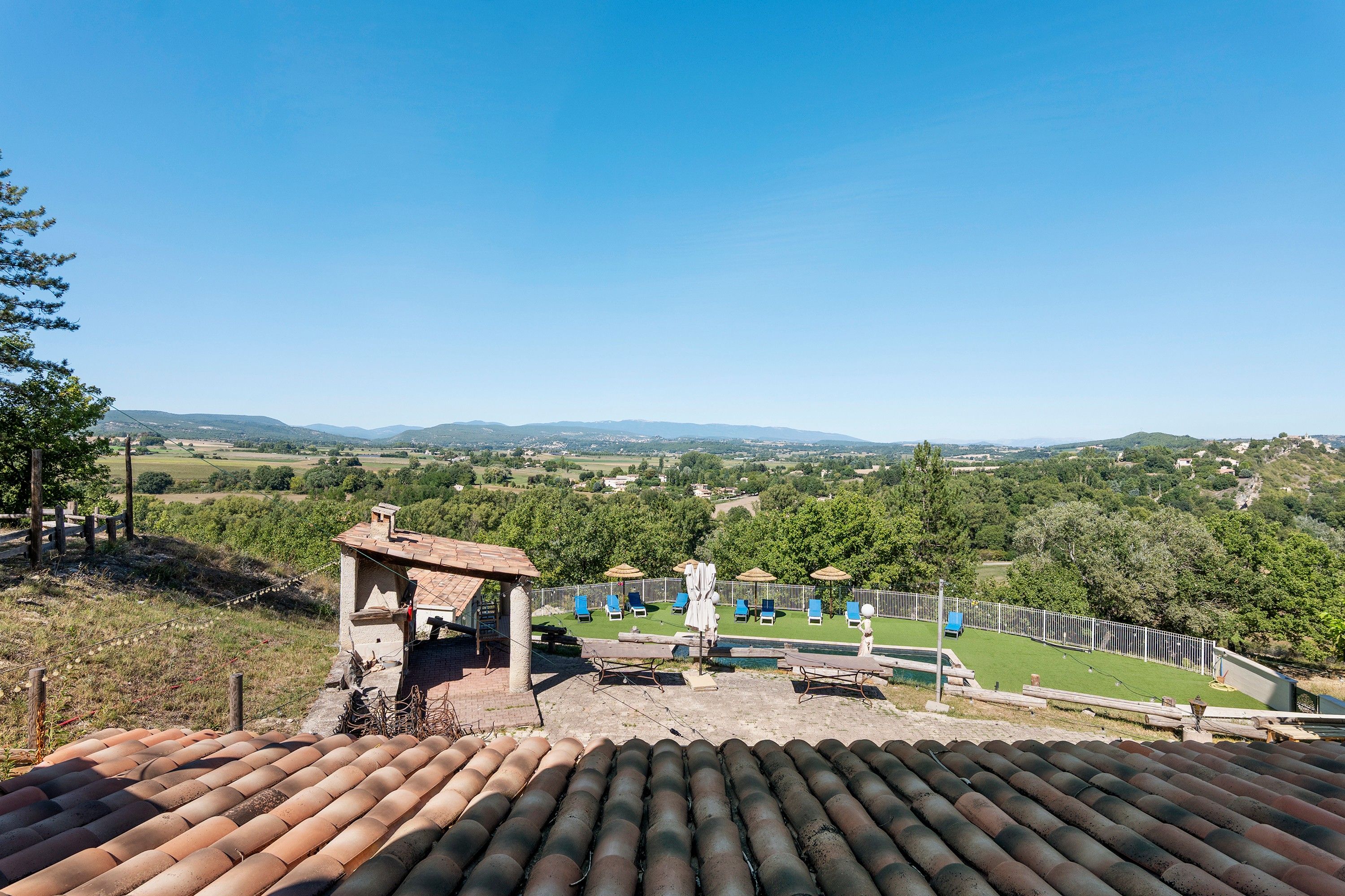 Une terrasse sur le toit offrant une vue sur un paysage rural, avec des champs et des collines à l’horizon.