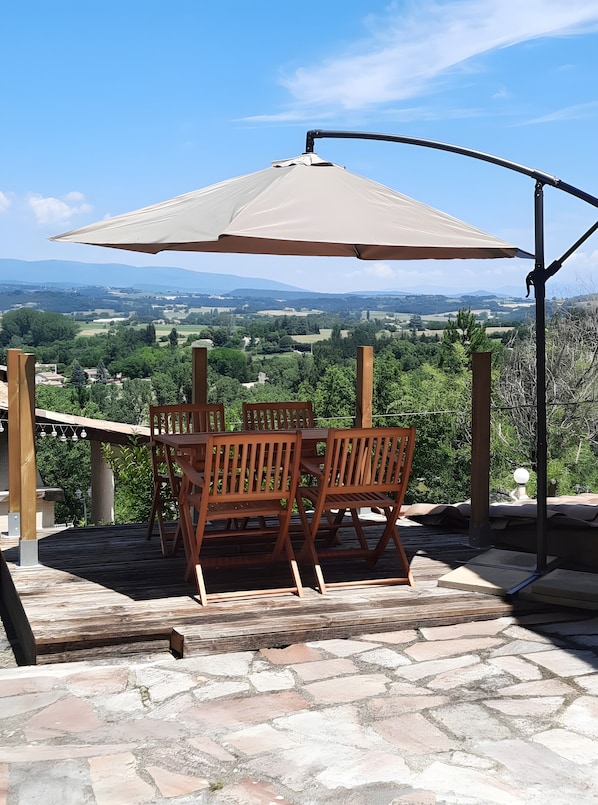 A patio with a table and chairs under a canopy, overlooking a scenic landscape.