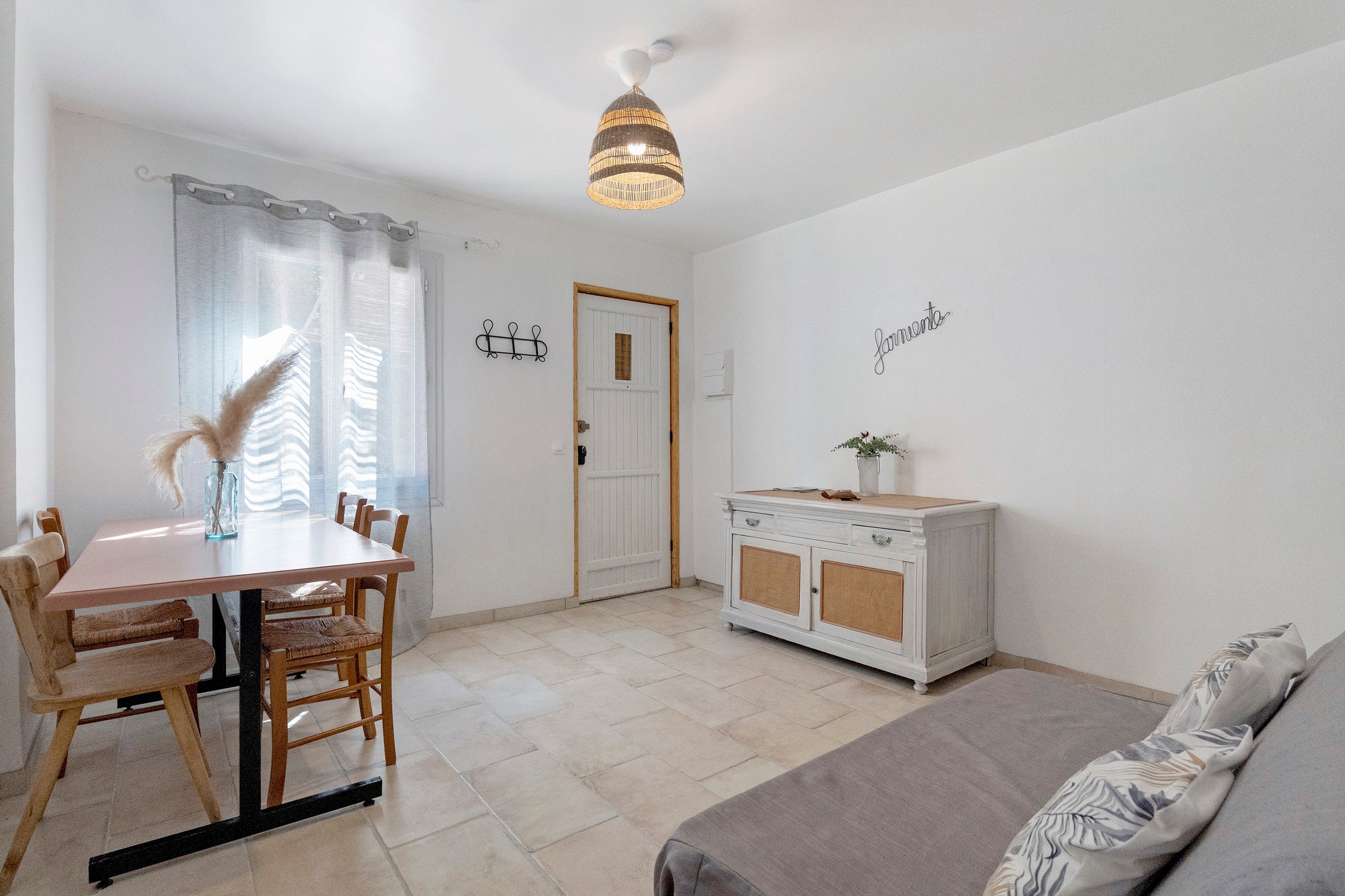 A room with a dining table, chairs, a sofa, a cabinet, and a door.