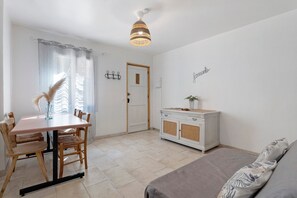Ein Zimmer mit Esstisch, Stühlen, einer Couch, einem Schrank und einer Tür.