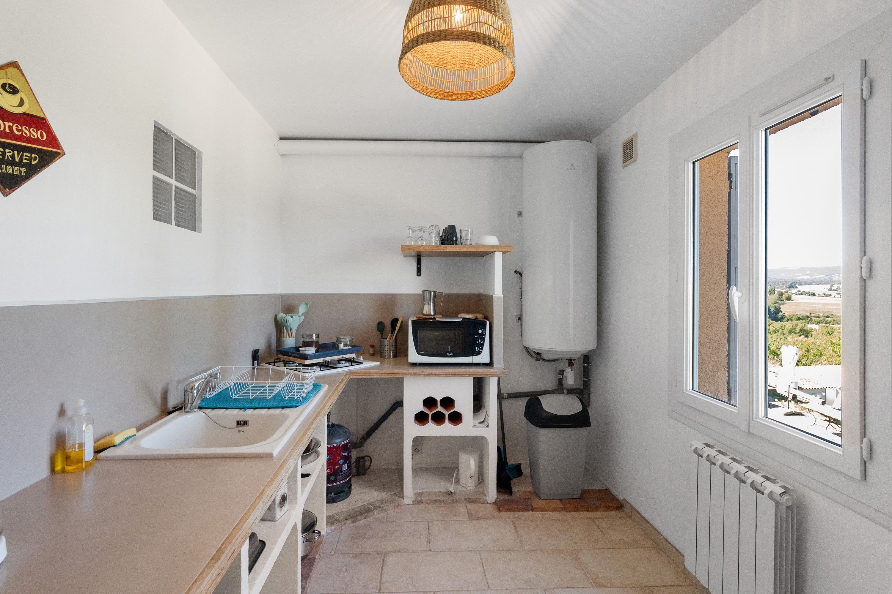 A compact kitchen with a sink, stove, microwave, and a window with a view.