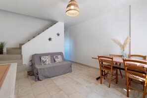 A modern interior with a staircase, a sofa with patterned cushions, a dining table with chairs, and a hanging light fixture. - Mas la bella vista - Relaxation with Stunning Valley Views (Dauphin)