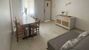 Une pièce comprenant une table à manger, des chaises, un canapé, un meuble et une porte.