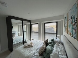 Quarto com uma cama grande, um espelho e uma janela com persianas.