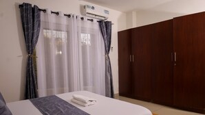 Un dormitorio con cama, cortinas, aire acondicionado y armario.