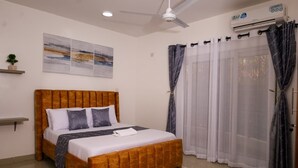 Un dormitorio con cama, ventilador de techo, unidad de aire acondicionado y ventana con cortinas.