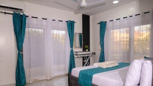 Un dormitorio con cama, cortinas, un escritorio y una ventana.