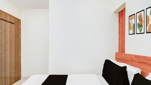 Ein Hotelzimmer mit einem Bett, einem Holzschrank und einer Wand mit gerahmten Kunstwerken.