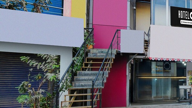 Eine Treppe führt zum Eingang eines Hotels, mit einem Metallgeländer und einer roten Wand.