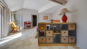 A room with a high ceiling, a wooden cabinet with drawers, a red lamp, and a chair. - Guest Room “Entre Loire et Cher” with Private Heated Pool, Private Terrace & Wi-Fi (Faverolles-sur-Cher)