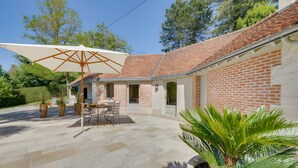 A patio with stone flooring, a table, chairs, and a large umbrella. - Guest Room “Entre Loire et Cher” with Private Heated Pool, Private Terrace & Wi-Fi (Faverolles-sur-Cher)