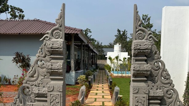 A pathway leading to a building with ornate stone pillars and a tiled entrance. - Eleven Eleven Villa (Auroville)