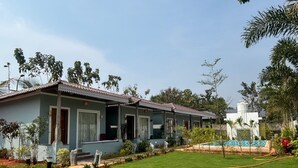 A two-story residential building with a tiled roof, a front porch, and a well-maintained lawn. - Eleven Eleven Villa (Auroville)