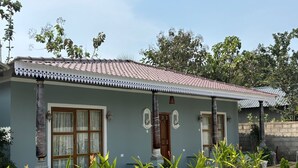 A house with a swimming pool, a tiled roof, and a garden with various plants. - Eleven Eleven Villa (Auroville)
