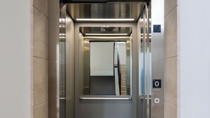 An elevator with a digital display, metallic interior, and a reflective floor. - Brezza Apartments (Santa Flavia)