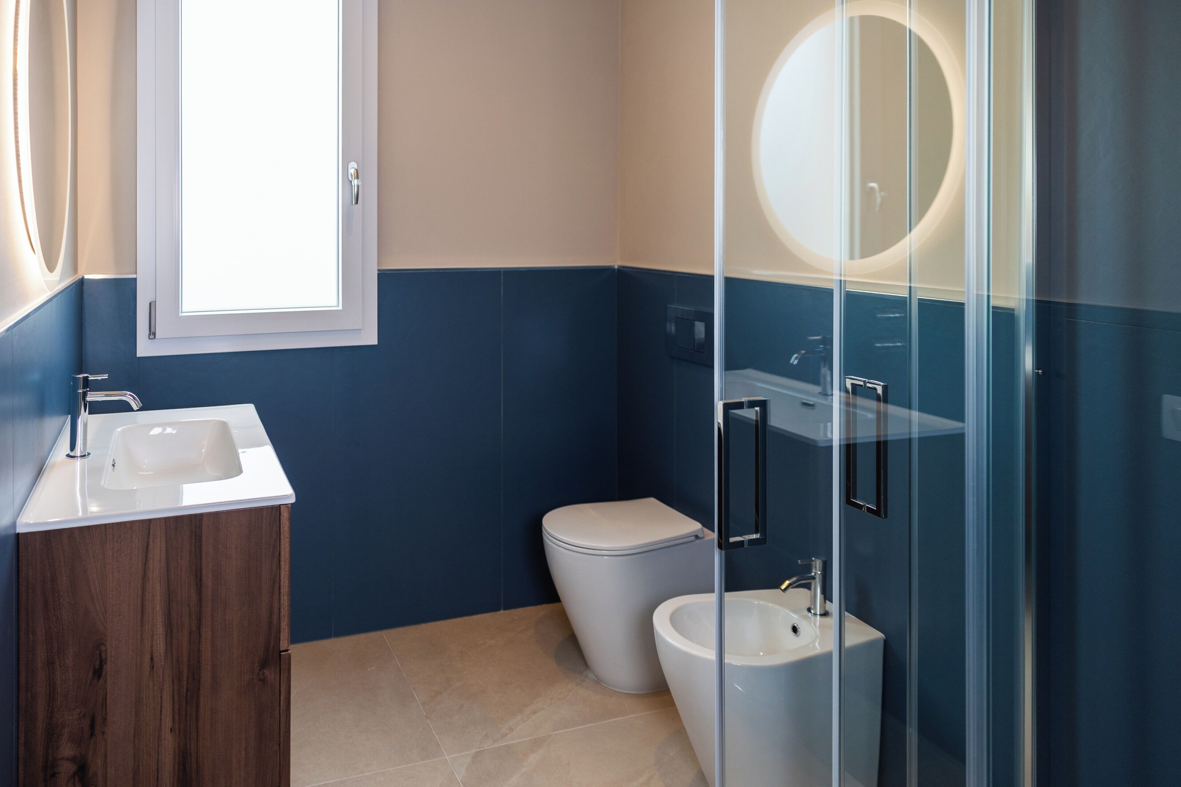Un bagno con lavandino, WC e cabina doccia in vetro.