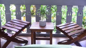 A balcony with two wooden lounge chairs and a small table with a potted plant. - Belvita Resort Ella (Ella)