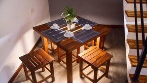 A wooden dining table with four chairs, a potted plant, and a staircase in the background. - Belvita Resort Ella (Ella)