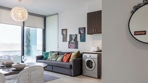 Eine moderne Wohnung mit Essbereich, Sofa, Waschmaschine und Bildern an den Wänden.