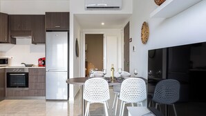 Eine moderne Küche mit Einbauofen, Mikrowelle und Kühlschrank. Ein Essbereich mit Tisch und Stühlen sowie ein flachbildfernseher an der Wand.