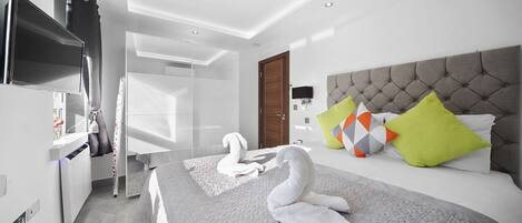 Una habitación de hotel moderna con una cama grande, un televisor de pantalla plana, un armario y un baño.