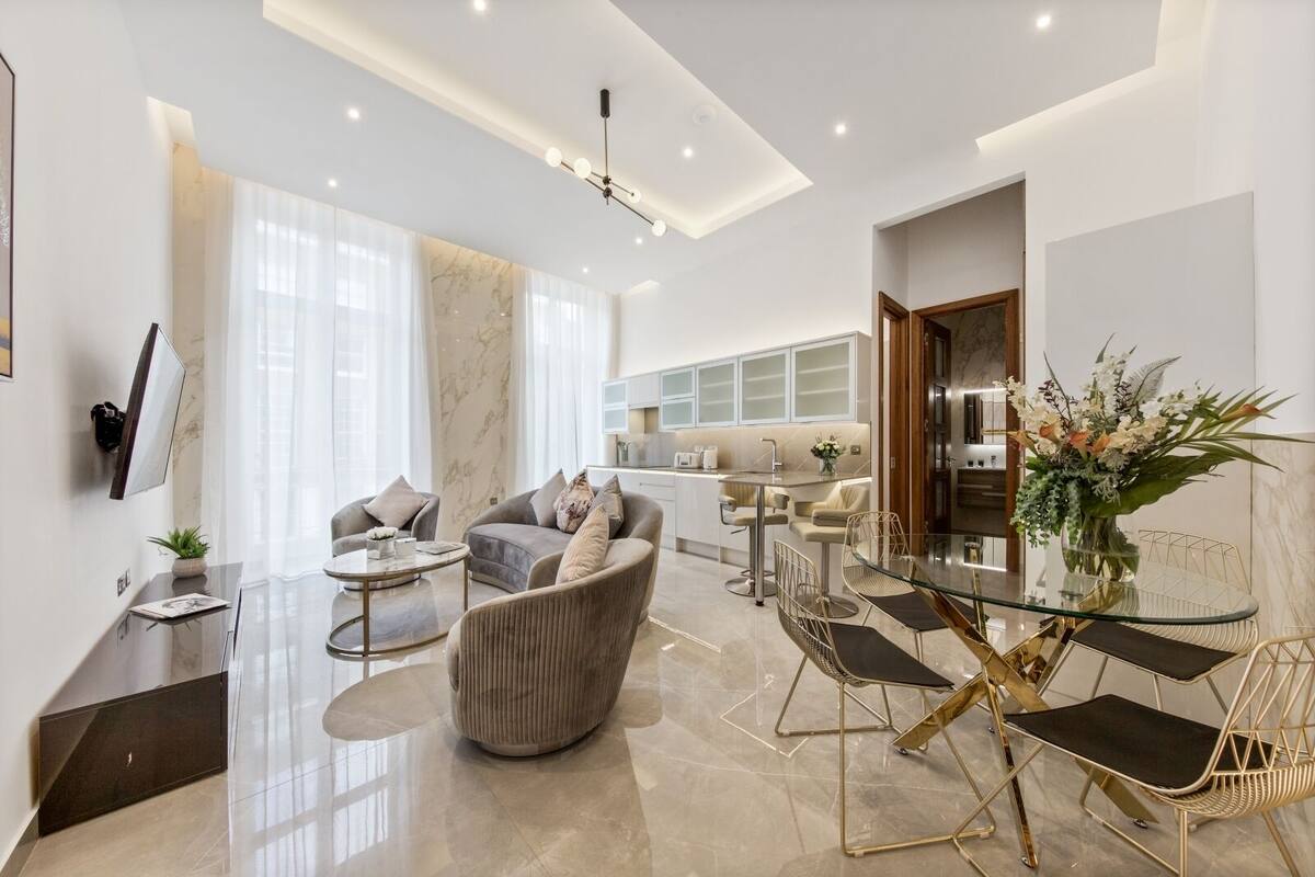A modern living room with a sofa, armchairs, a coffee table, and a dining area with a glass table and chairs.