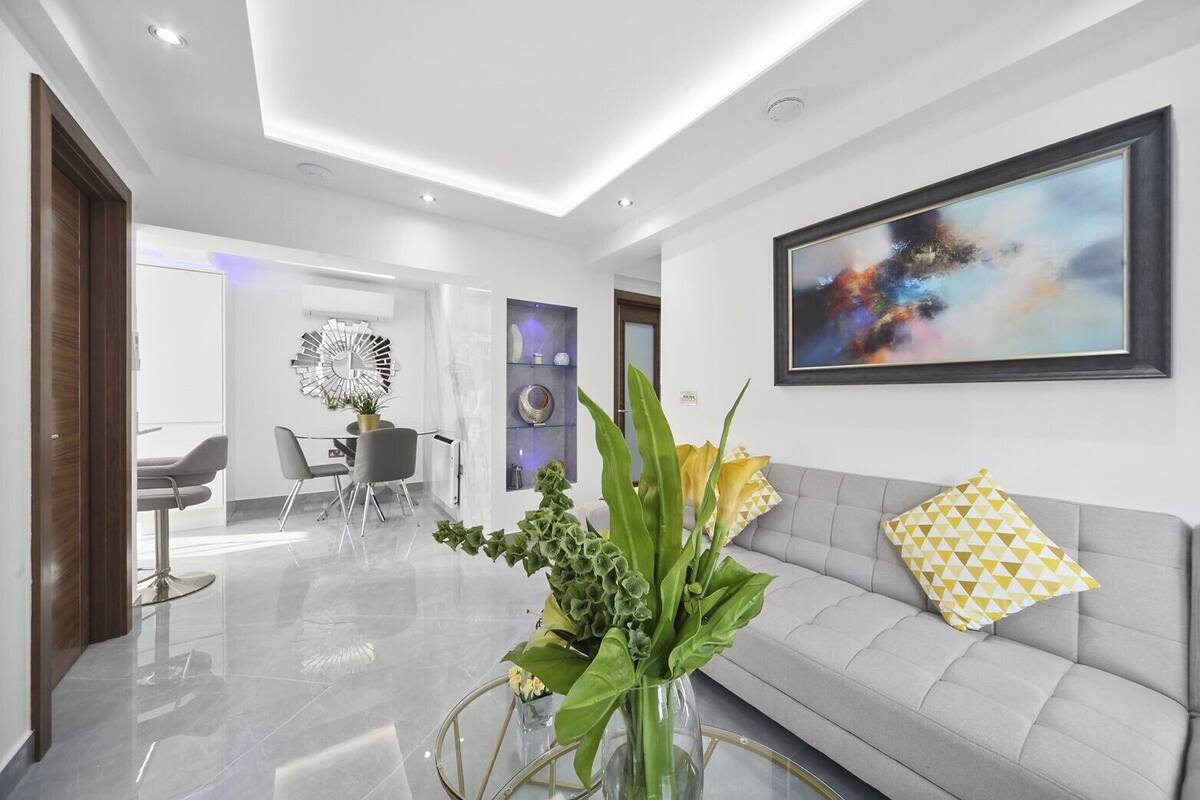 A modern interior with a sofa, a dining area, and a large abstract painting on the wall.