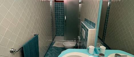 Baño con lavabo, espejo y cabina de ducha.