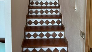 Eine Treppe mit gemusterten Fliesen, die zu einer Holztür führt.