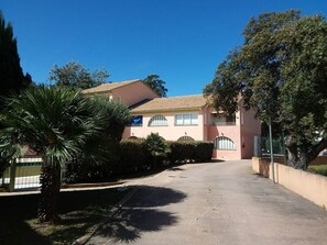 A two-story building with a driveway leading to the entrance. - Holiday Home 'Apartment Les Jardins De La Mer' with Shared Pool, Wi-Fi and Air Conditioning (Linguizzetta)