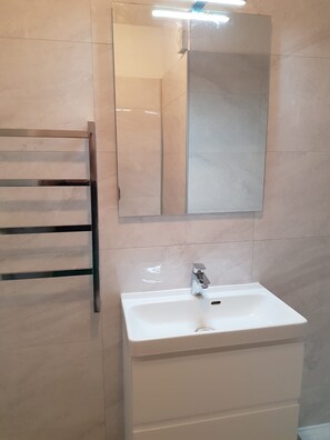 A bathroom with a white sink, a mirror, and a towel rack. - Holiday Home 'Apartment Les Jardins De La Mer' with Shared Pool, Wi-Fi and Air Conditioning (Linguizzetta)