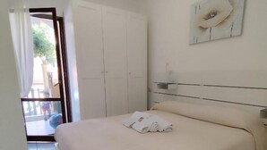 Une chambre à coucher avec un lit, des rideaux blancs, une porte et une œuvre d’art accrochée au mur.