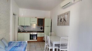 Une pièce de taille modeste comprenant un lit, une table à manger avec des chaises, un coin cuisine et un luminaire au plafond.