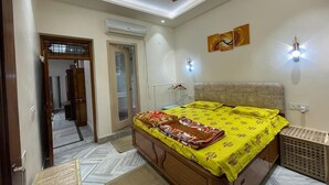 Ein Schlafzimmer mit einem Bett, Deckenventilator, Wandleuchten und einer Tür zu einem anderen Raum.