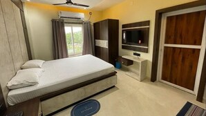 A hotel room with a bed, a TV, a ceiling fan, an air conditioning unit, and a sliding door.