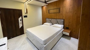 A bedroom with a bed, a ceiling fan, a nightstand, and a wooden accent wall.