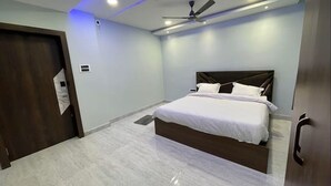 A bedroom with a bed, ceiling fan, and a door. - HOTEL RK INTERNATIONAL (Baripada)