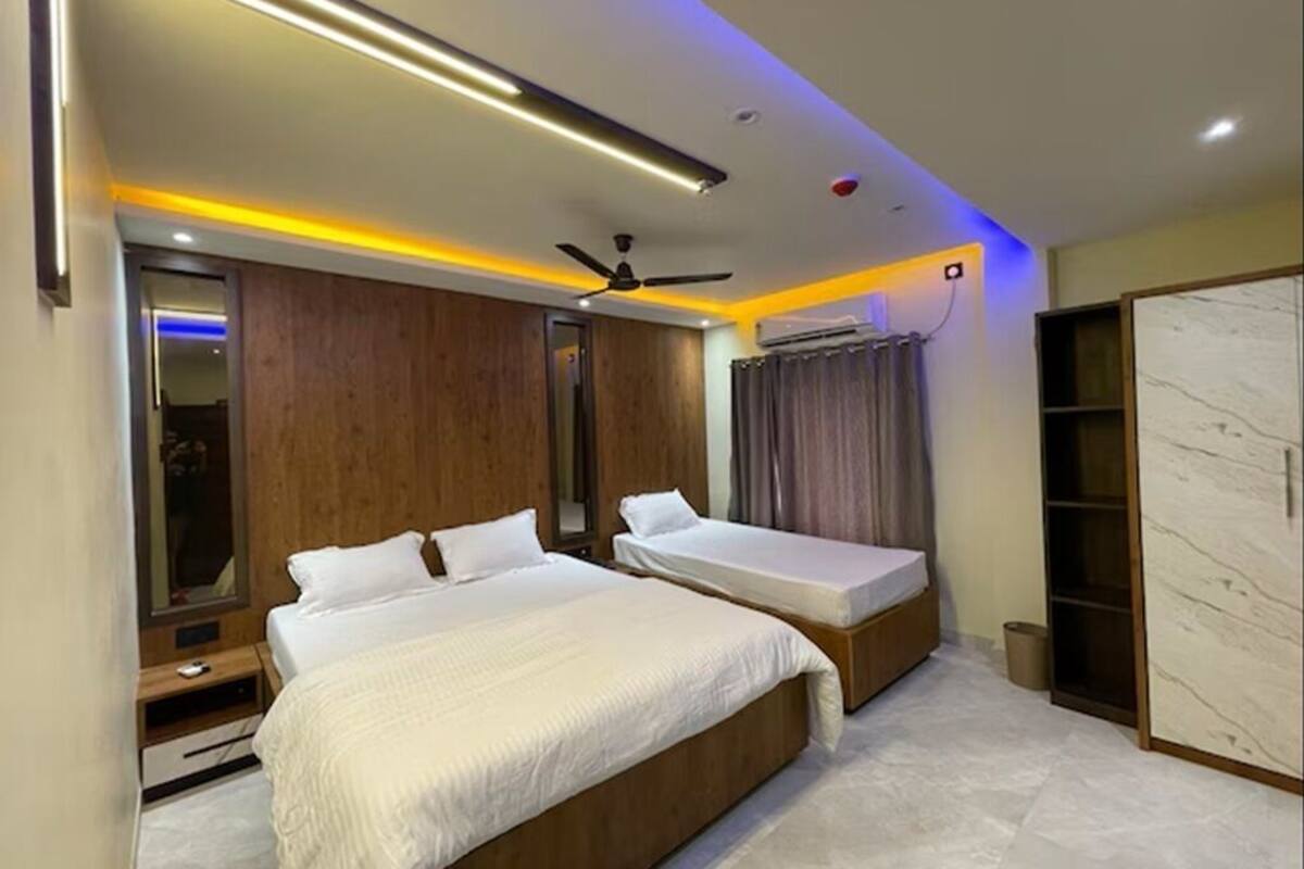 A modern bedroom with two beds, a ceiling fan, and a built-in wardrobe.