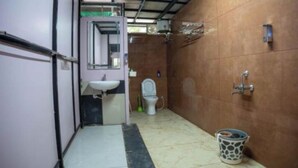 A narrow bathroom with a sink, toilet, and shower area.