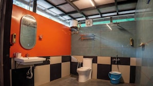 A bathroom with a sink, toilet, and shower area, featuring checkered walls and a visible ceiling fan.