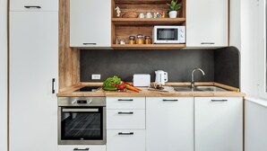 Eine moderne Küche mit weißen Schränken, einer Holz Arbeitsplatte, einem Backofen, einer Mikrowelle und einem Spülbecken.