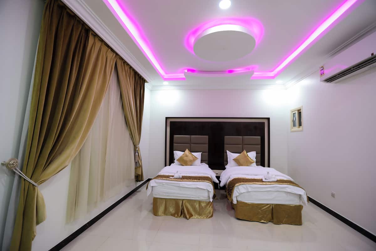A hotel room with two beds, a large headboard, and a ceiling with circular lighting.
