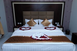 A neatly made bed with a heart-shaped decoration on the pillows and a swan-shaped decoration on the bed.
