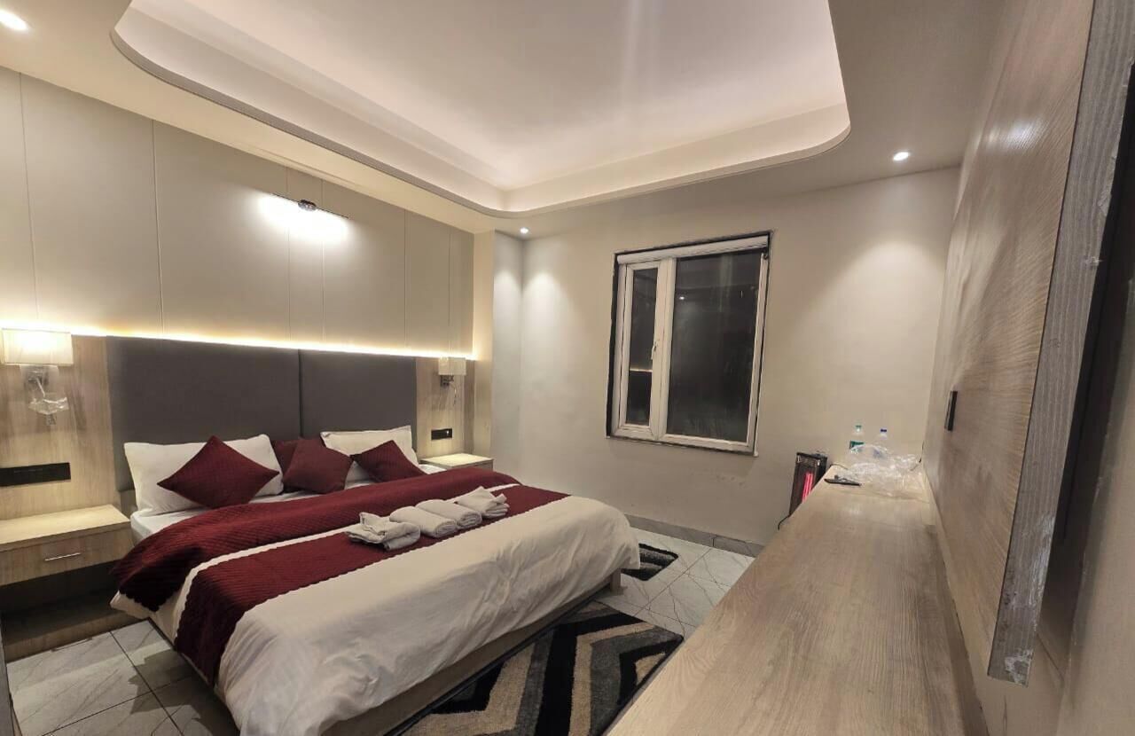 Ein modernes Hotelzimmer mit einem großen Bett, Nachttischen, einem Fenster und einer Deckenleuchte.