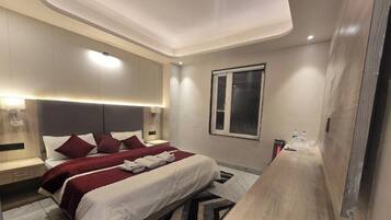 Ein modernes Hotelzimmer mit einem großen Bett, Nachttischen, einem Fenster und einer Deckenleuchte.